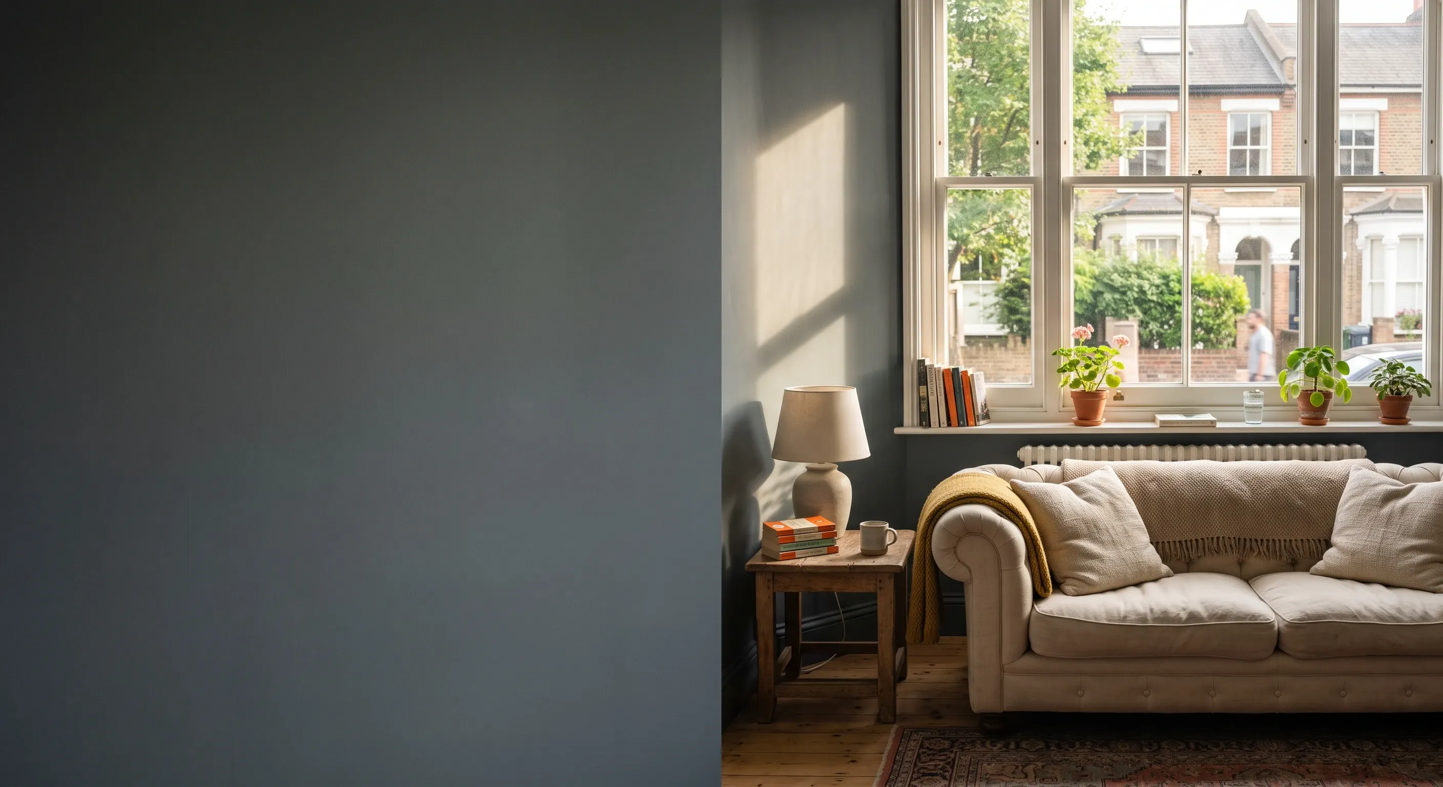 A finished London living room with a plain wall on the left and a sofa by the window on the right.