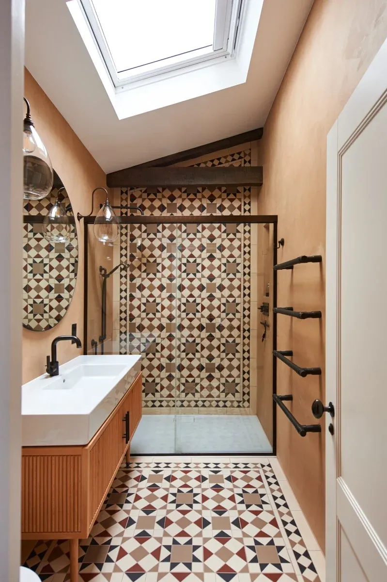 Loft shower room with patterned Victorian-style tiles and skylight, designed by Zebra