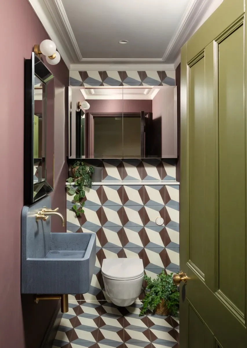 Bold cloakroom with geometric tiles, gold fittings and pink and olive tones by Zebra