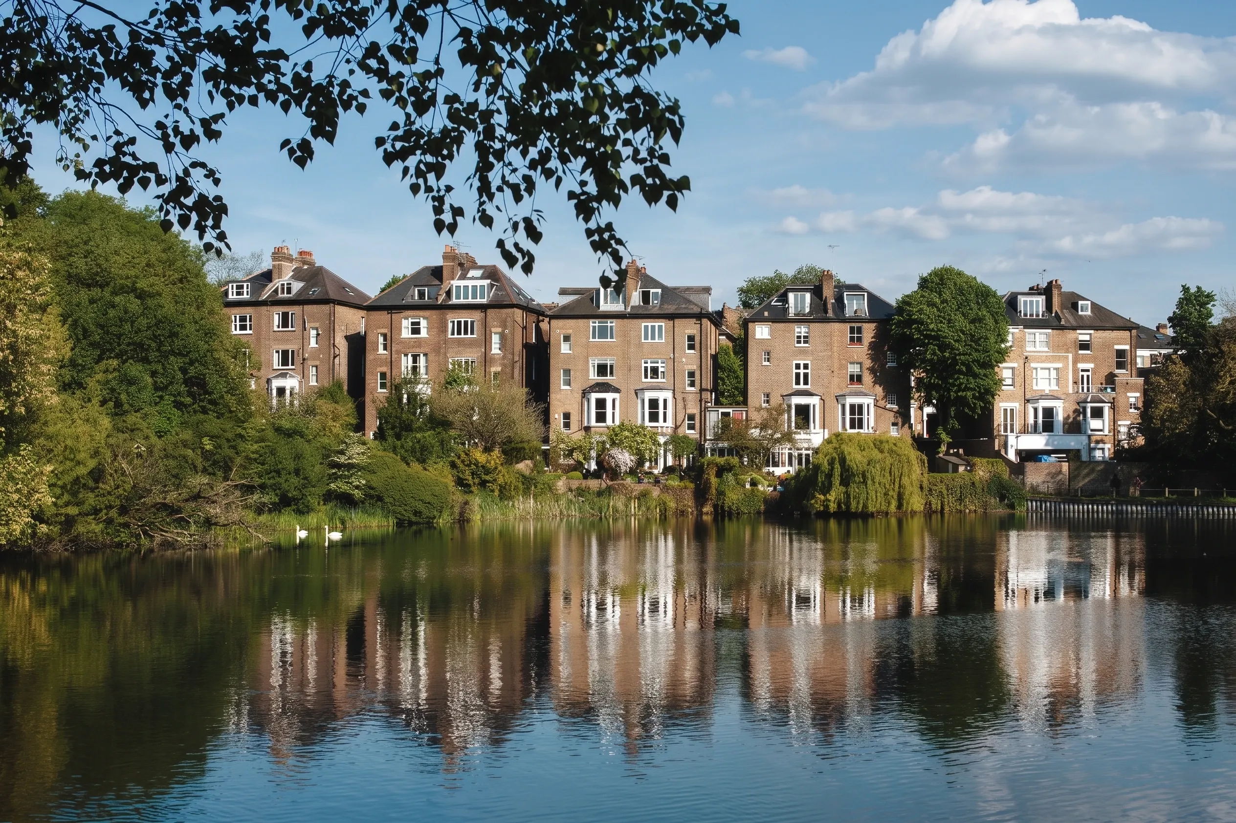 Large Victorian brick houses backing onto one of the Hampstead ponds, reflected in still water with swans and a willow on the far bank.