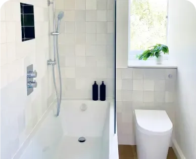 A white tiled bathroom with a bath and loo