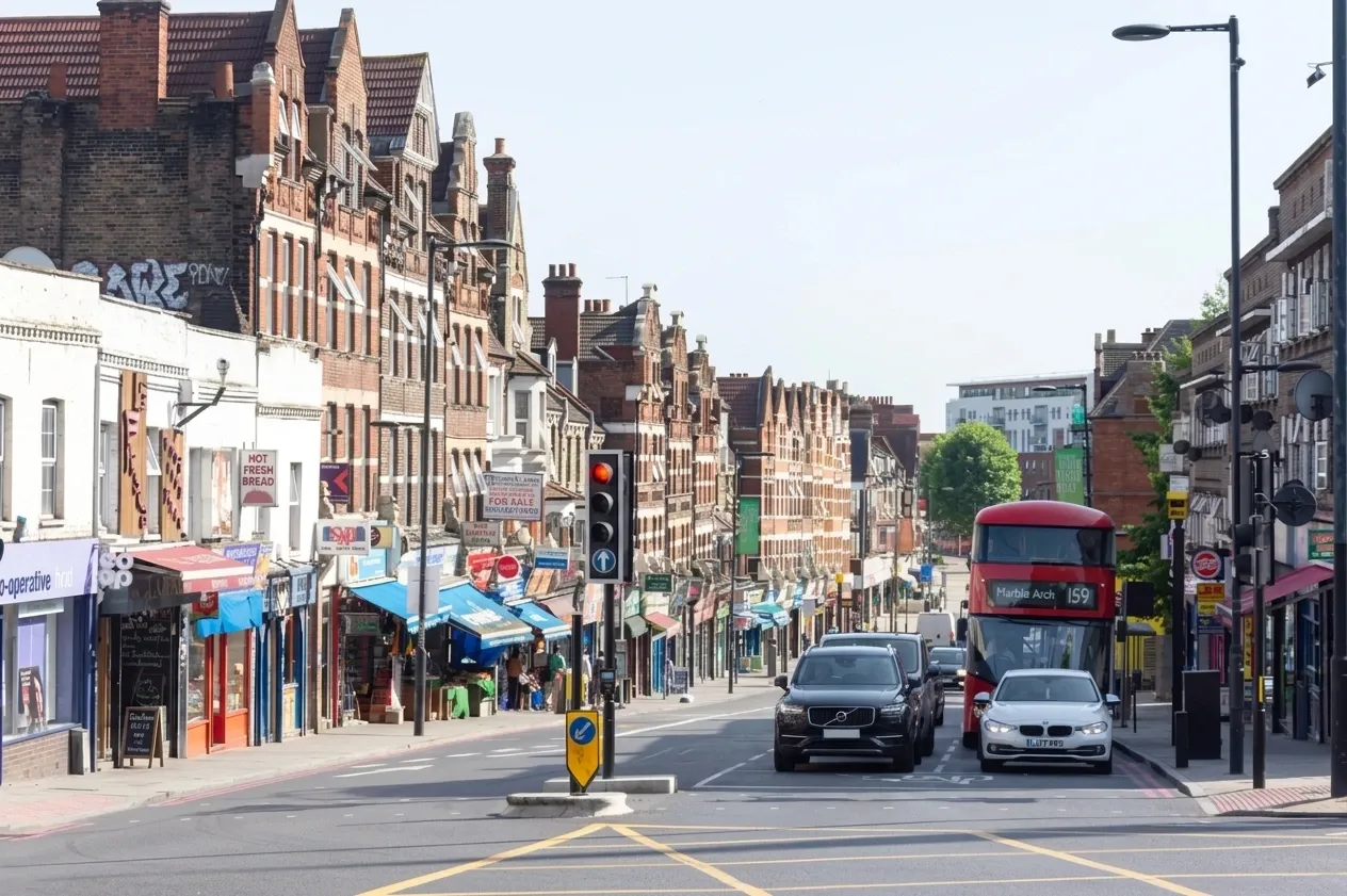 Victorian shopfronts and gabled upper floors along Streatham High Road, with a 159 bus to Marble Arch heading north.